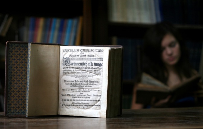 Image: Girl Reading Next to Old Book